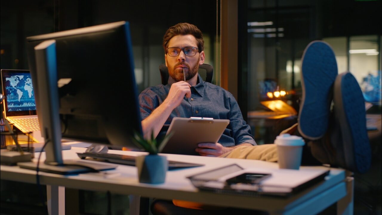 Caucasian business man trader businessman analyst writing document in night office paperwork overtime evening working online trading thinking write notes thoughtful guy male developer think ideas task